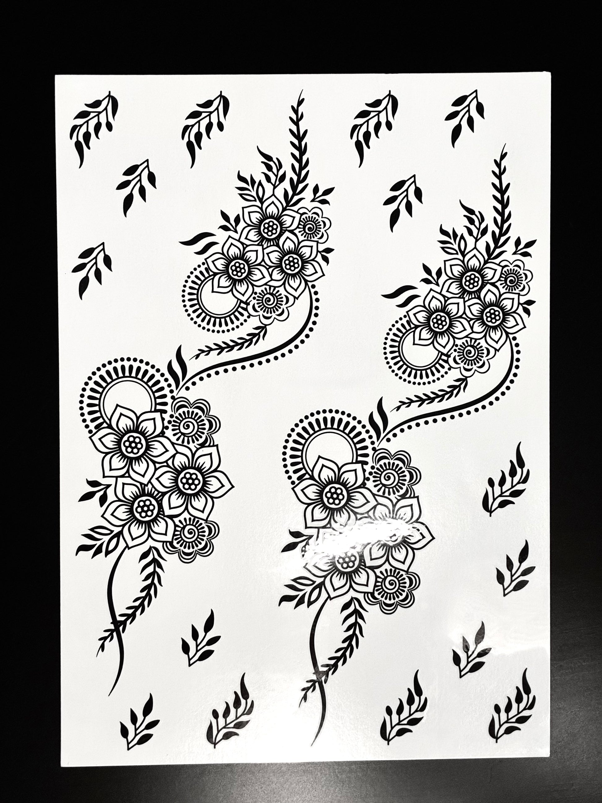 Black paisley henna transfer sheet with floral motifs, detailed mehndi patterns, and decorative filler elements.