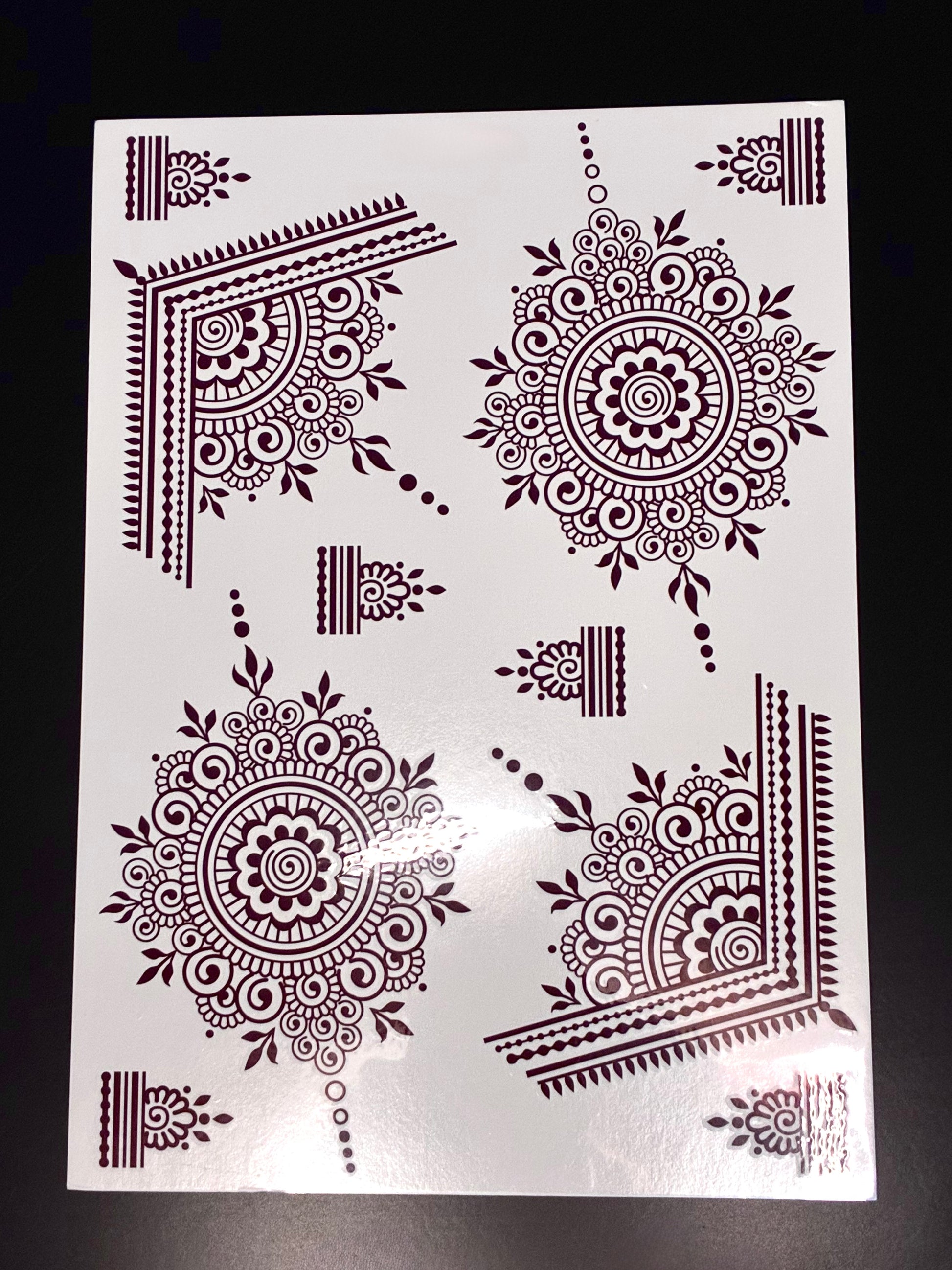 Red mandala henna transfer sheet with intricate circular mehndi designs and decorative corner patterns.